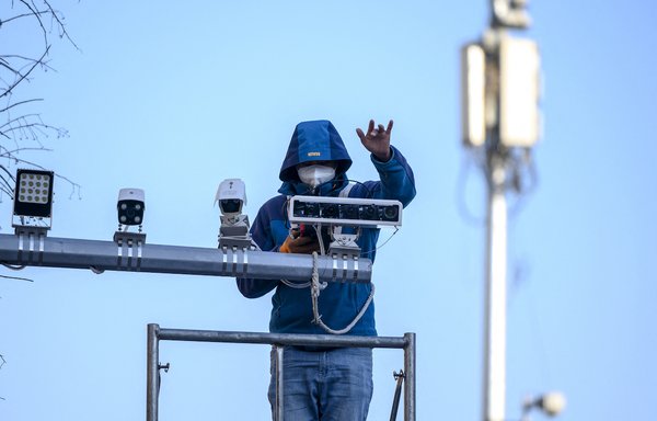 A worker installs closed circuit TV cameras in Beijing. Huawei is central to Beijing's face-recognition programme in Xinjiang, China, where millions of Muslims have been forced into 're-education camps. and subjected to torture, rape and other abuses. [Noel Celis/AFP]