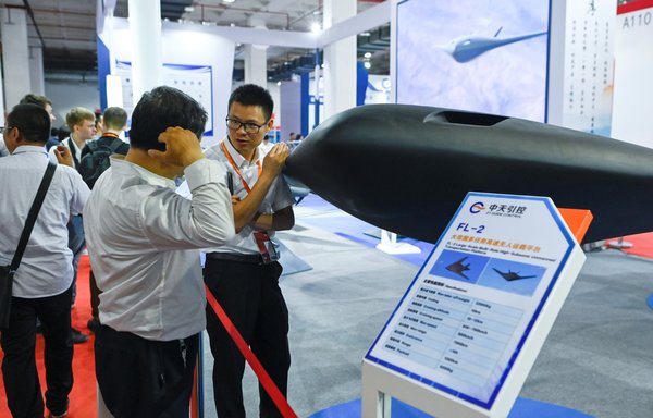 A staff member introduces a model of the FL-2 stealth transport drone to a visitor at the Chinese Defence Information Equipment and Technology exhibition in Beijing in 2019. [Wang Zhao/AFP]