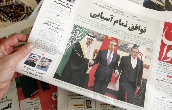 A man in Tehran holds a local newspaper reporting on its front page the China-brokered deal between Iran and Saudi Arabia, signed in Beijing the previous day, on March 11. [Atta Kenare/AFP]