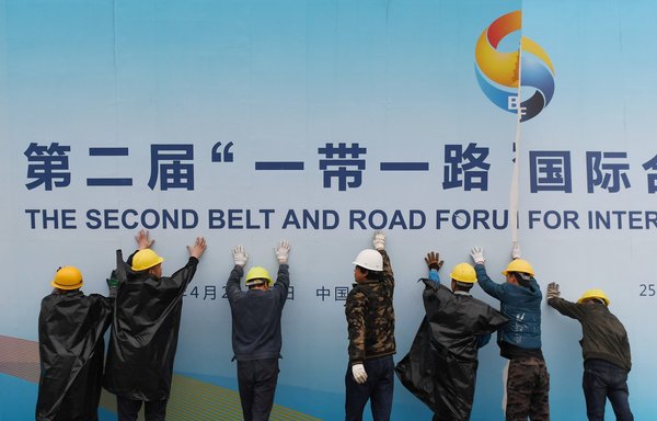Workers take down a Belt and Road Forum panel outside the venue of the forum in Beijing on April 27, 2019. [AFP]