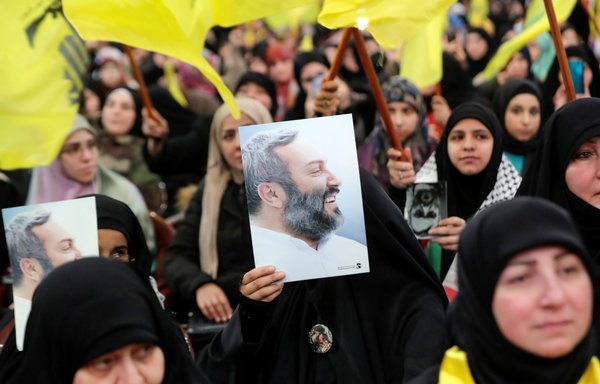 Women raise Hizbullah's flag and pictures of slain commander Imad Mughniyeh during a rally commemorating killed senior members of the party in Beirut's southern suburb on February 16. [Anwar Amro/AFP]