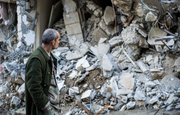 A man walks past a collapsed building in the town of Jableh in Syria's northwestern province of Latakia following an earthquake, on February 7. Some experts say Iran is attempting to cash in on the chaos caused by the earthquake. [AFP]