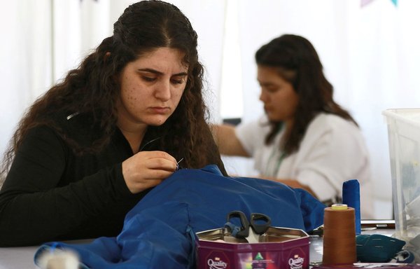 Iraqi women work on garments at the Rafedin sewing project in Amman, based at St. Joseph Catholic church, on March 12. [Khalil Mazraawi/AFP]