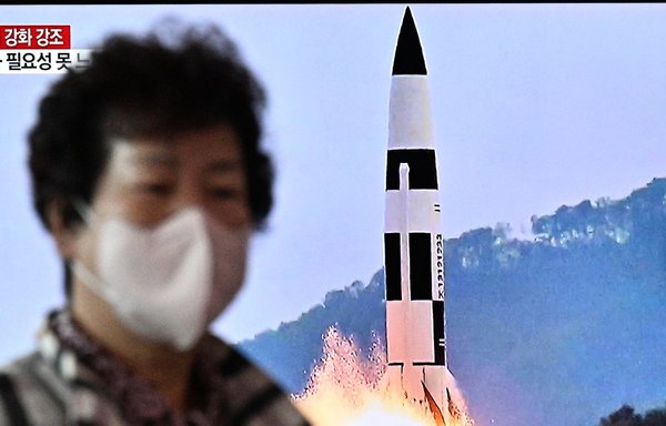 A woman walks past a television showing a news broadcast with a photo of a Hokkaido missile launch training test by the North Korean People's Army Tactical Nuclear Operation Unit at an undisclosed location, at a railway station in Seoul, South Korea, on October 10. [Anthony Wallace/AFP]