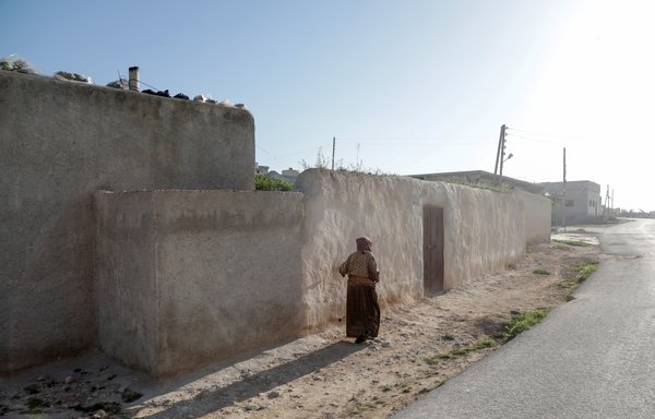 A woman walks past a house following a US helicopter raid on an ISIS leader in a village near Jarablus, in northern Syria's Aleppo province, on April 17. [Bakr Alkasem/AFP]