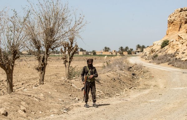 An SDF fighter stands guard on a road on the outskirts of the village of al-Baghouz in Syria's northern Deir Ezzor province, on March 24, 2021. [Delil Souleiman/AFP]