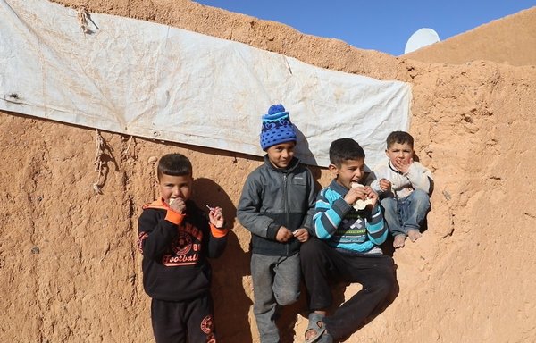 در روز ٢٨ اسفندماه، کودکان در کنار خانه‌ای گلی در اردوگاه الرکبان که جایگزین چادرهایی شده است که در اثر طوفان از جا کنده شده بودند، با هم تکه نانی را می‌خورند. [ارتش آزاد سوریه]