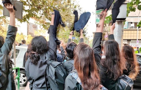 Iranian students take off the compulsory head covering in front of their high school. [Independent Persian]