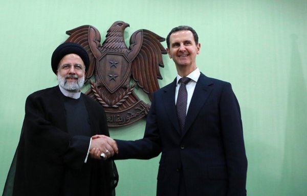 Syria's President Bashar al-Assad shakes hands with his Iranian counterpart Ebrahim Raisi in Damascus on May 3. [Louai Beshara/AFP]