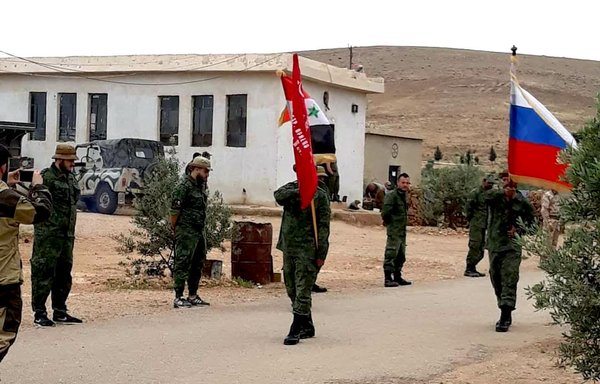 Mercenaries recruited by a Russian-controlled private security company raise Syrian and Russian flags in the Syrian desert, in a photo circulated on social media.