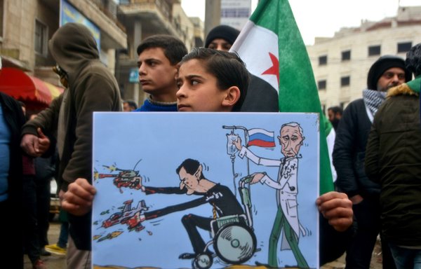 A young Syrian holds a caricature that shows Syrian president Bashar al-Assad and Russian President Vladimir Putin as he takes part in a February 21, 2020 demonstration in the city of Idlib to protest against the Syrian regime and Russian assault on the province. [Mohammed al-Rifai/AFP]