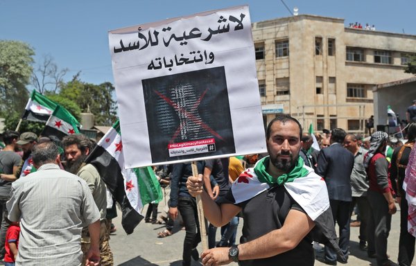 Syrians demonstrate against what they call the illegitimate elections in the opposition held city of Idlib on May 26, 2021, as voting began across Syria for an election guaranteed to return president Bashar al-Assad for a fourth term in office. [Omar Haj Kadour/AFP]