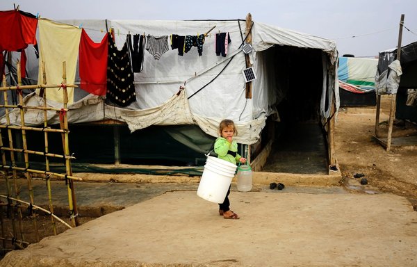 A child stands outside a tent in a makeshift camp for Syrian refugees in Talhayat in the Akkar district in northern Lebanon on October 26. [Ibrahim Chalhoub/AFP]