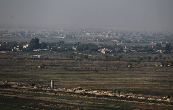 A picture taken November 12, 2018, from al-Qaim in Iraq shows the Syrian border town of Albu Kamal in Deir Ezzor province, Syria. [Ahmad al-Rubaye/AFP]