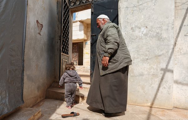 Ibrahim Othman is seen here on March 22 with a girl he had found abandoned at the doorstep of the village mosque on February 11, 2020. He decided to raise her with his wife, at his home in Hazano village in Idlib province. [Omar Haj Kadour/AFP]