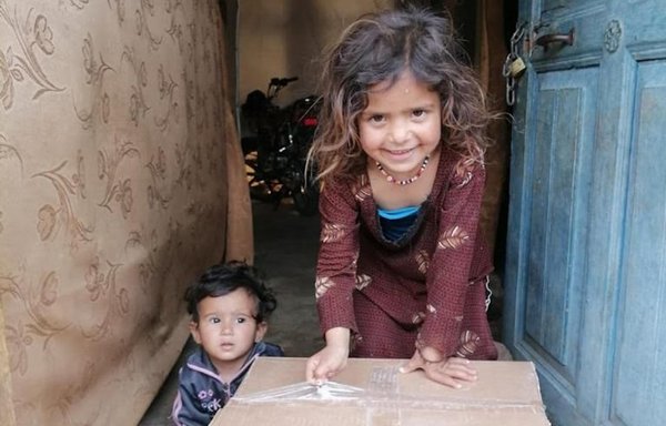 A girl and her brother receive a food ration from Ajialouna Association, which helps impoverished families in Lebanon by distributing monthly food rations and securing daily meals for them in its kitchen. [Ajialouna Association]