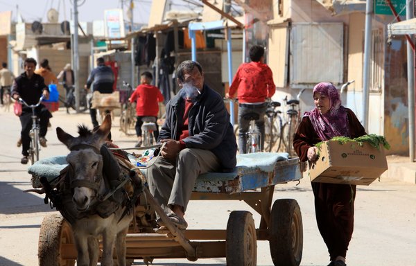 لاجئون سوريون يمارسون أعمالهم في مخيم الزعتري للاجئين في الأردن يوم 13 آذار/مارس. [محمد أبو غوش]