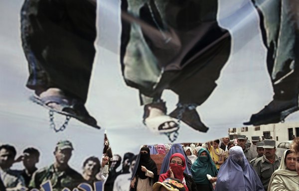 Afghan protesters march behind a torn banner depicting people executed by hanging during a demonstration at the Iranian embassy in Kabul on May 6, 2010. Nearly 300 people took part in the protest fuelled by their claim that Iran had executed 45 Afghan citizens recently. [Mauricio Lima/AFP]