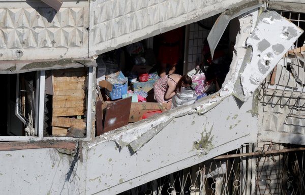 A resident inspects her belongings in a damaged residential building after a Russian drone attack in Odesa, Ukraine, on June 10. [Oleksandr Gimanov/AFP]