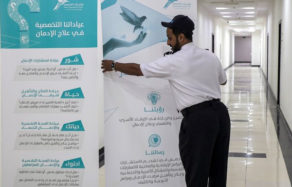 A security guard places information banners at the Rushd Specialised Centre for Family Counselling in Riyadh on June 15. The private clinic treats patients for drug addiction. [Fayez Nureldine/AFP]