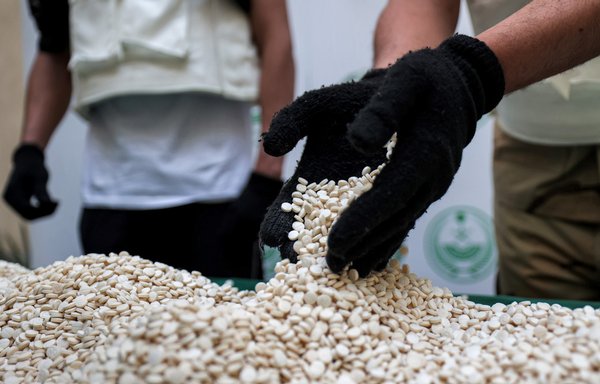 Saudi Directorate of Narcotics Control officers on March 1, 2022, sort through Captagon tablets seized during a special operation raid in Jeddah. [Fayez Nureldine/AFP]