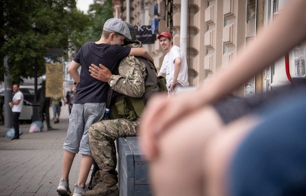 A young boy hugs a member of the Wagner Group in Rostov-on-Don on June 24. [Roman Romokhov/AFP]