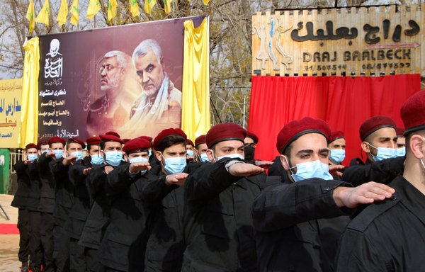Members of Lebanese Hizbullah take part in a parade under a large poster of the late Iraqi paramilitary commander Abu Mahdi al-Muhandis and IRGC Quds Force commander Qassem Soleimani on January 2, 2021, in the Lebanese city of Baalbek. [AFP]