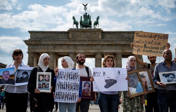 Activists and relatives of Syrians suspected of being detained or disappeared by the Syrian regime pose with portraits of missing Syrians during a demonstration in front of Berlin's Brandenburg gate on May 7, 2022. [John MacDougall/AFP]