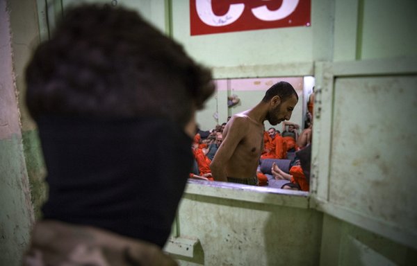 عنصر من قوات سوريا الديموقراطية يقف بالقرب من عناصر داعش المسجونين في سجن بمحافظة الحسكة يوم 26 تشرين الأول/أكتوبر 2019. [فاضل سنا/وكالة الصحافة الفرنسية]