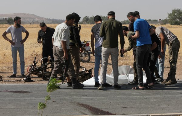 Passersby and gunmen gather around a body at the site of a reported drone strike in the town of Bazaa near al-Bab in Syria's Aleppo province on July 7. A US drone strike killed an ISIS leader in Syria after Russian warplanes harassed MQ-9 drones over the country, US Central Command said July 9. [Bakr Alkasem/AFP]