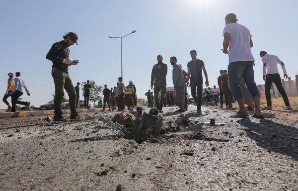 Passersby and gunmen gather at the site of a reported drone strike in Bazaa near al-Bab in Syria's Aleppo province on July 7. [Bakr Alkasem/AFP]