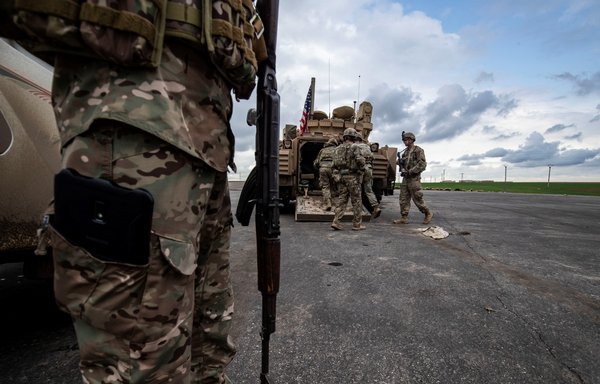 A member of the Syrian Democratic Forces (SDF) and US soldiers are pictured near an armoured military vehicle on the outskirts of Rumaylan in Syria's al-Hasakeh province on March 27. [Delil Souleiman/AFP]