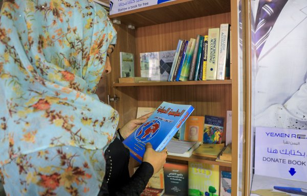 مواطنة يمنية تتفحص كتابا بمكتبة صغيرة في صنعاء في 29 أيلول/سبتمبر 2020. وأظهر اليمنيون اهتماما شبه معدوم بتعلم اللغة الفارسية في السنوات الماضية بسبب الصراع بين الثقافة العربية والثقافة الفارسية. [محمد حويس/وكالة الصحافة الفرنسية]