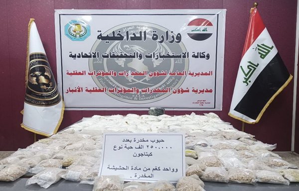 Security forces in Anbar province display Captagon pills and kilogramme they seized June 28 inside a school under construction in Ramadi. [Iraqi Ministry of Interior]