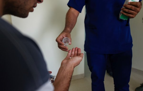 A patient receives his doze of medication from a health worker at Al-Canal Centre for Social Rehabilitation in Baghdad on July 11, where some 40 patients are being treated amid a dramatic increase in drug consumption and abuse in Iraq. [Ahmad al-Rubaye/AFP]