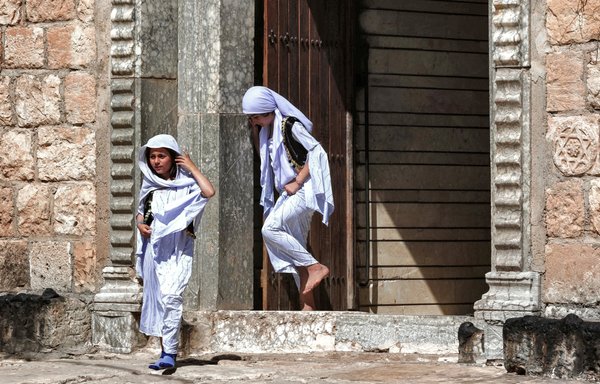 Girls walk out of a building as Iraqi Yazidis gather for a ceremony marking the Yazidi New Year at the Temple of Lalish near Dohuk on April 18. [Safin Hamid/AFP]