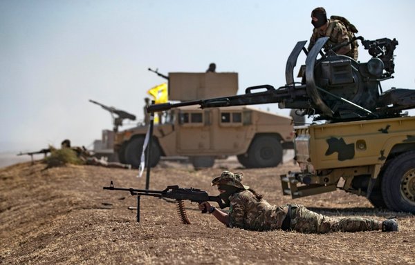 A fighter of the Syrian Democratic Forces (SDF) aims a machine gun while lying prone during a joint military exercise with forces of the international coalition against ISIS in the countryside of the town of al-Malikiya in Syria's northeastern al-Hasakeh province on September 7. [Delil Souleiman/AFP]